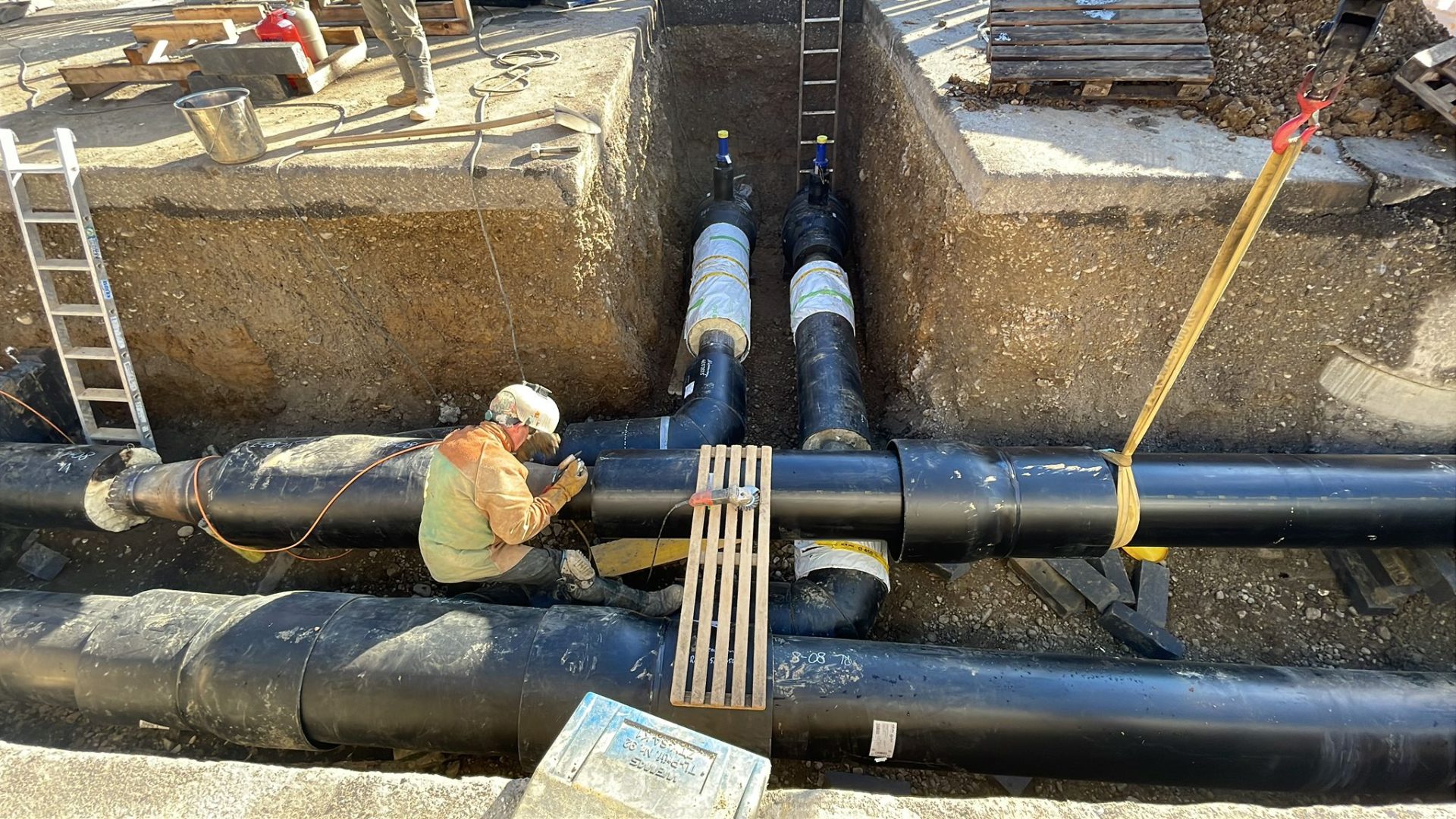 Zwei Männer schweißen ein Rohr am Straßenrand.